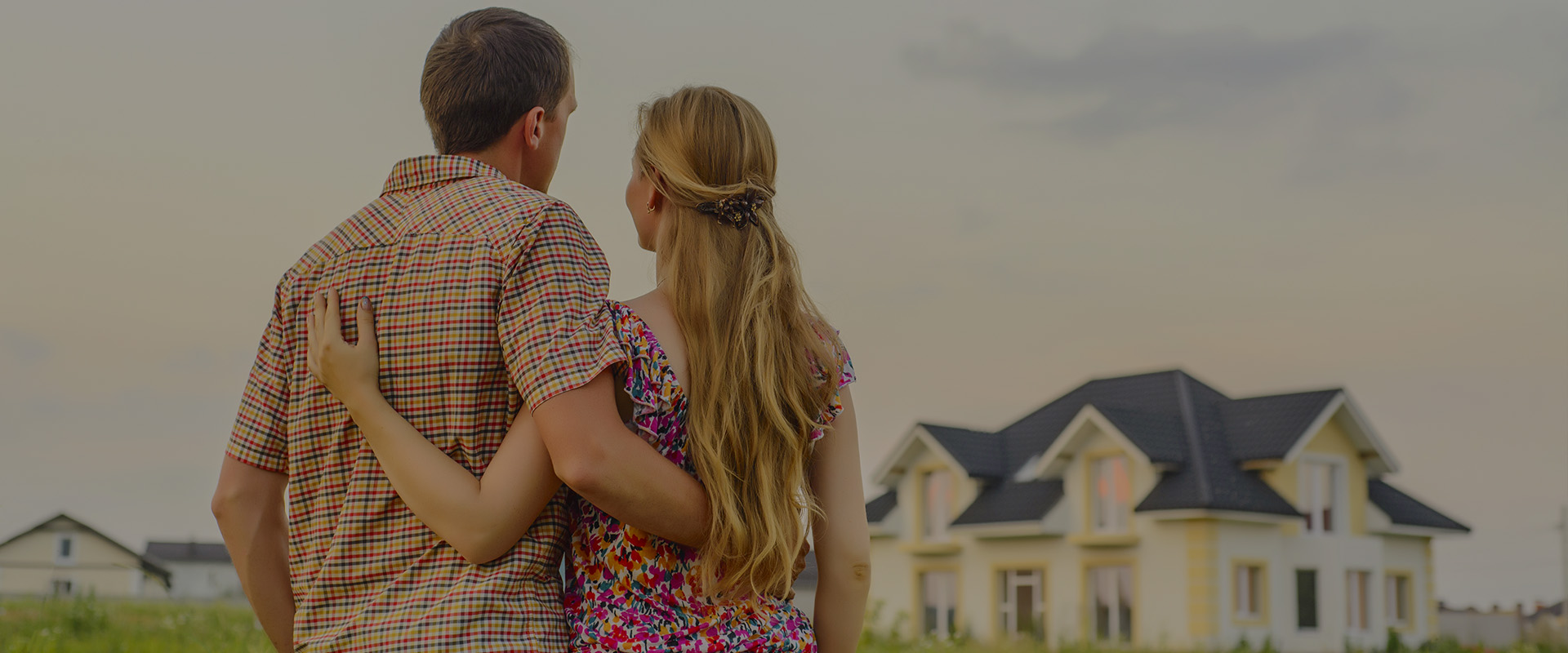 A man and woman embracing in front of their new home